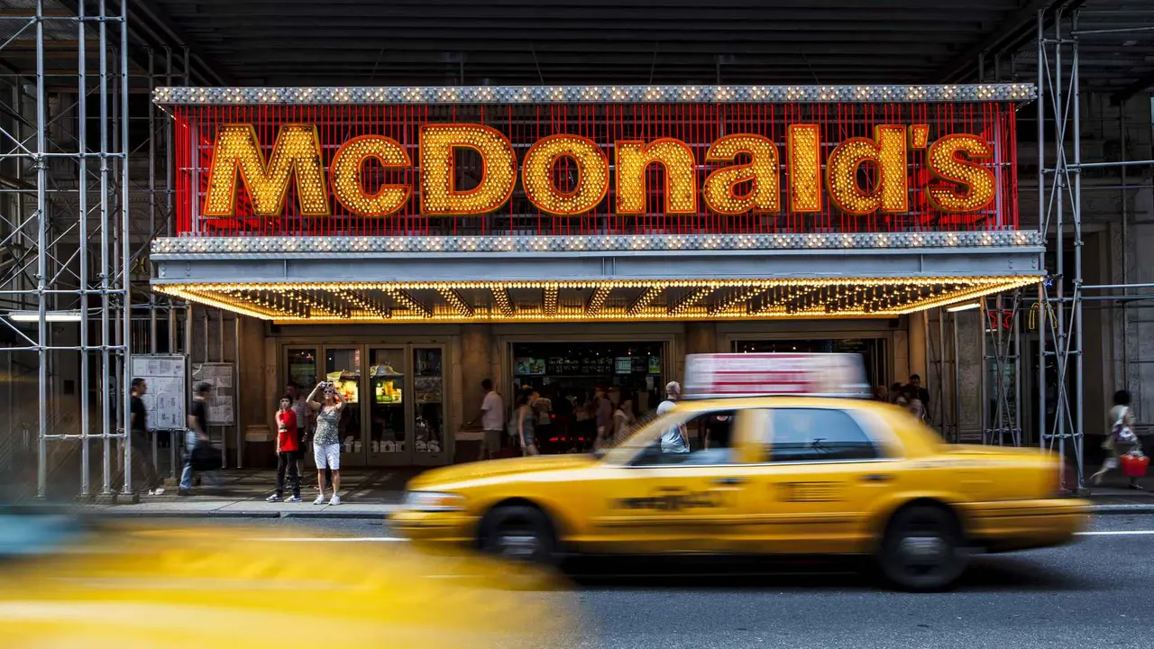 New York City, USA - September 4, 2011: Large group of people and yellow taxis passing by at the entrance to McDonalds fast-food restaurant in Midtown Manhattan, New York.