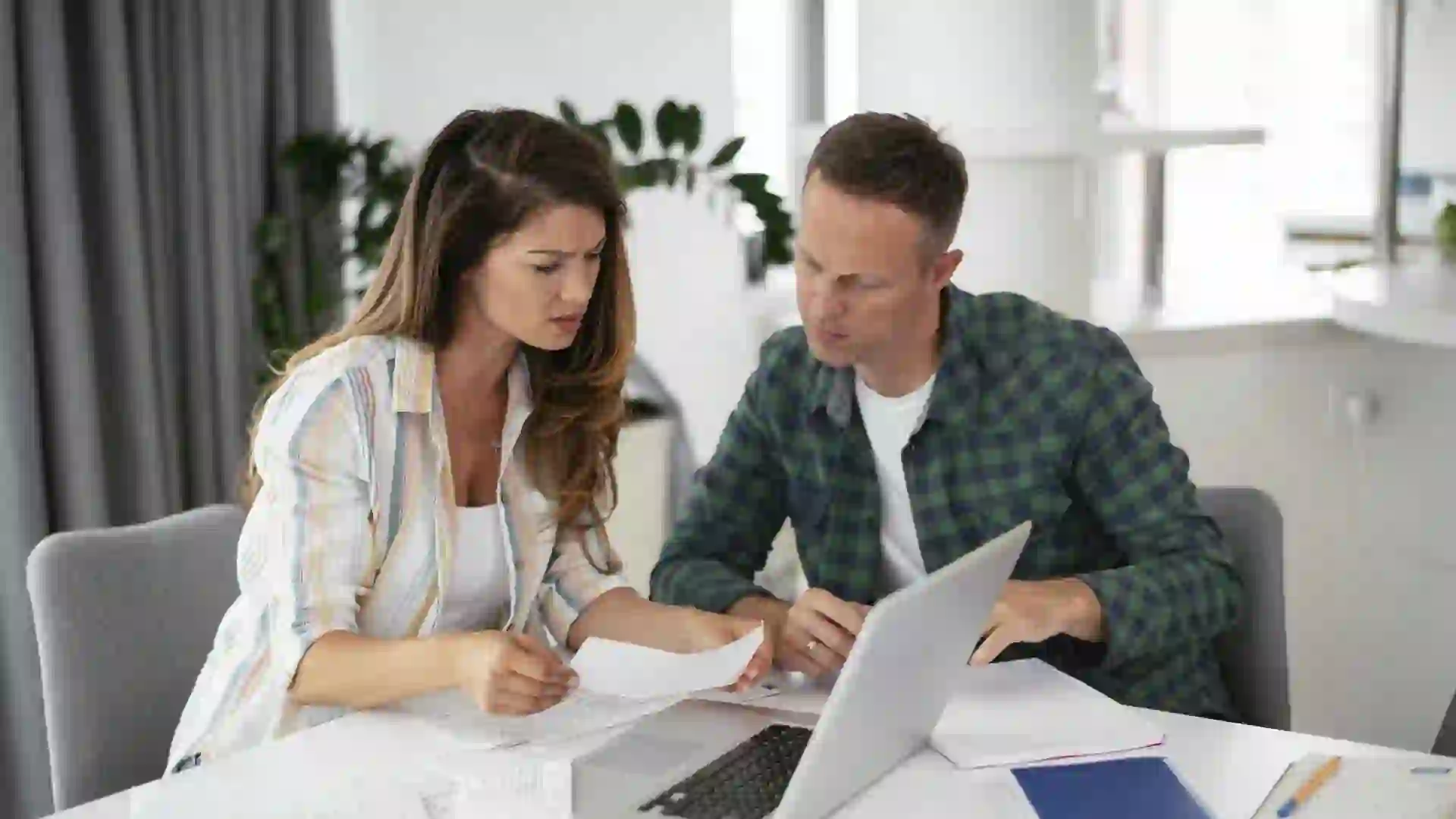 A couple goes over their finances while sitting in front of their laptop.