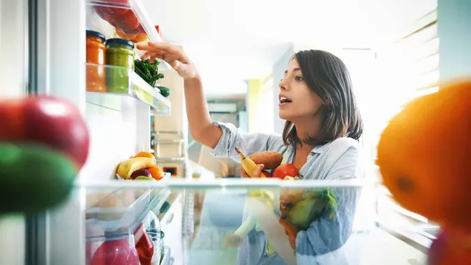 Closeup of a cheerful young couple picking some fruit and veggies from the fridge to make some healthy breakfast on Sunday morning.
