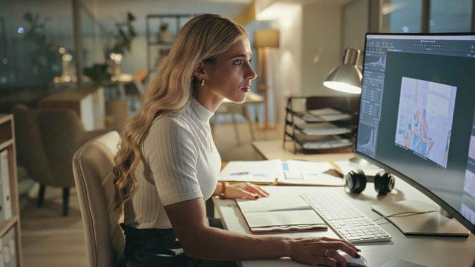 Business woman, night and graphic designer on computer in office at table working on deadline.