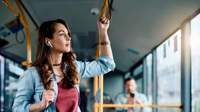 Young woman listening music over earbuds while commuting by city bus.