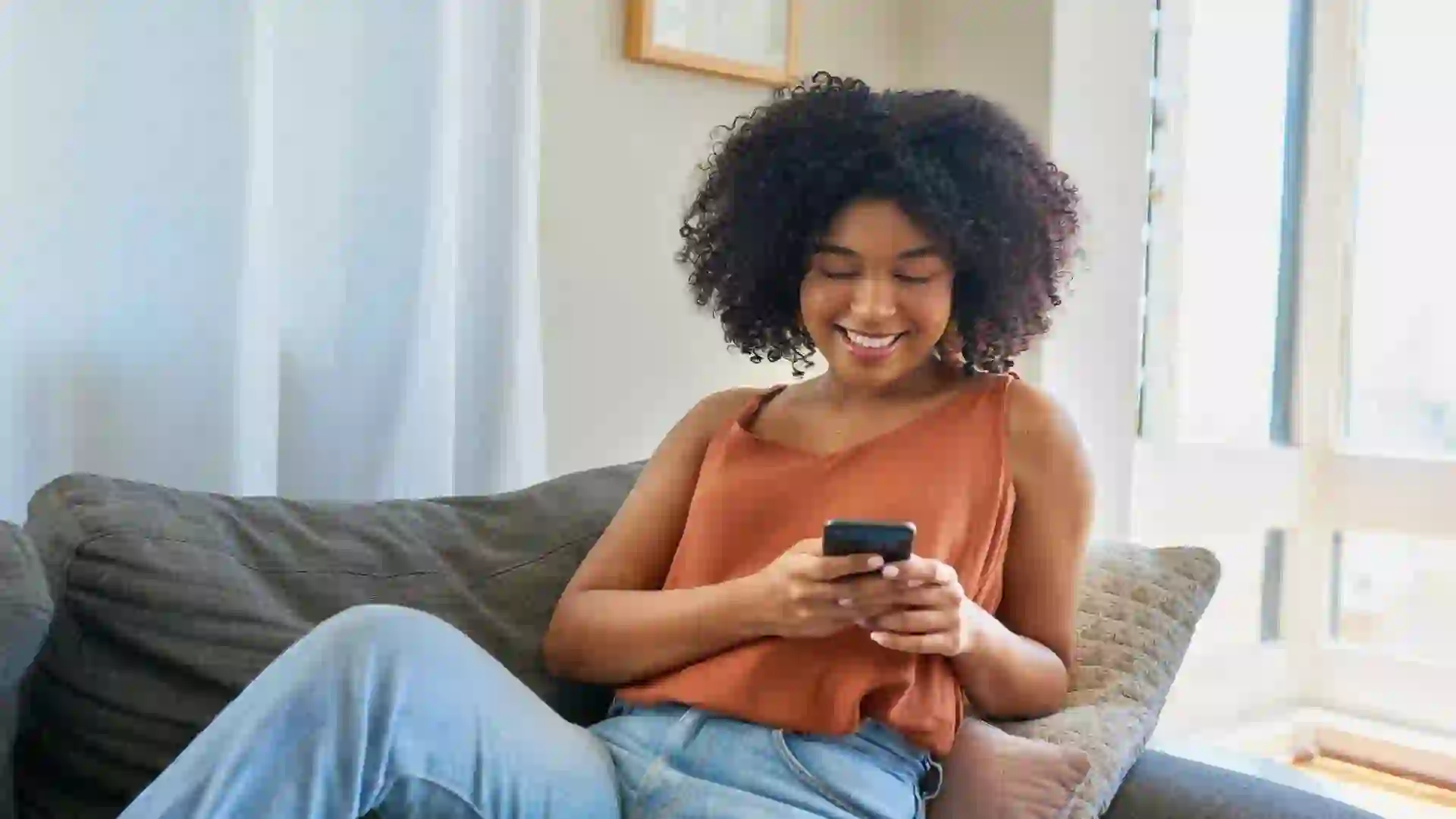 Shot of a young woman using a cellphone while relaxing on a sofa at home.