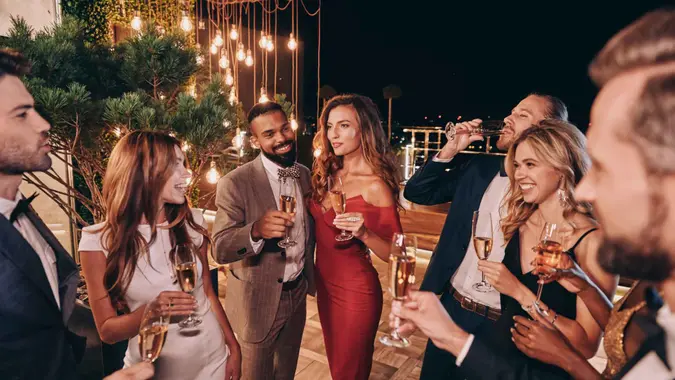 Group of beautiful young people in formalwear communicating and smiling while spending time on luxury party.