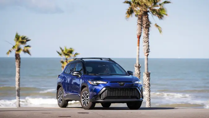 2024 Toyota Corolla Hybrid SE in a blue crush metallic color parked on the beach for promotional photo.