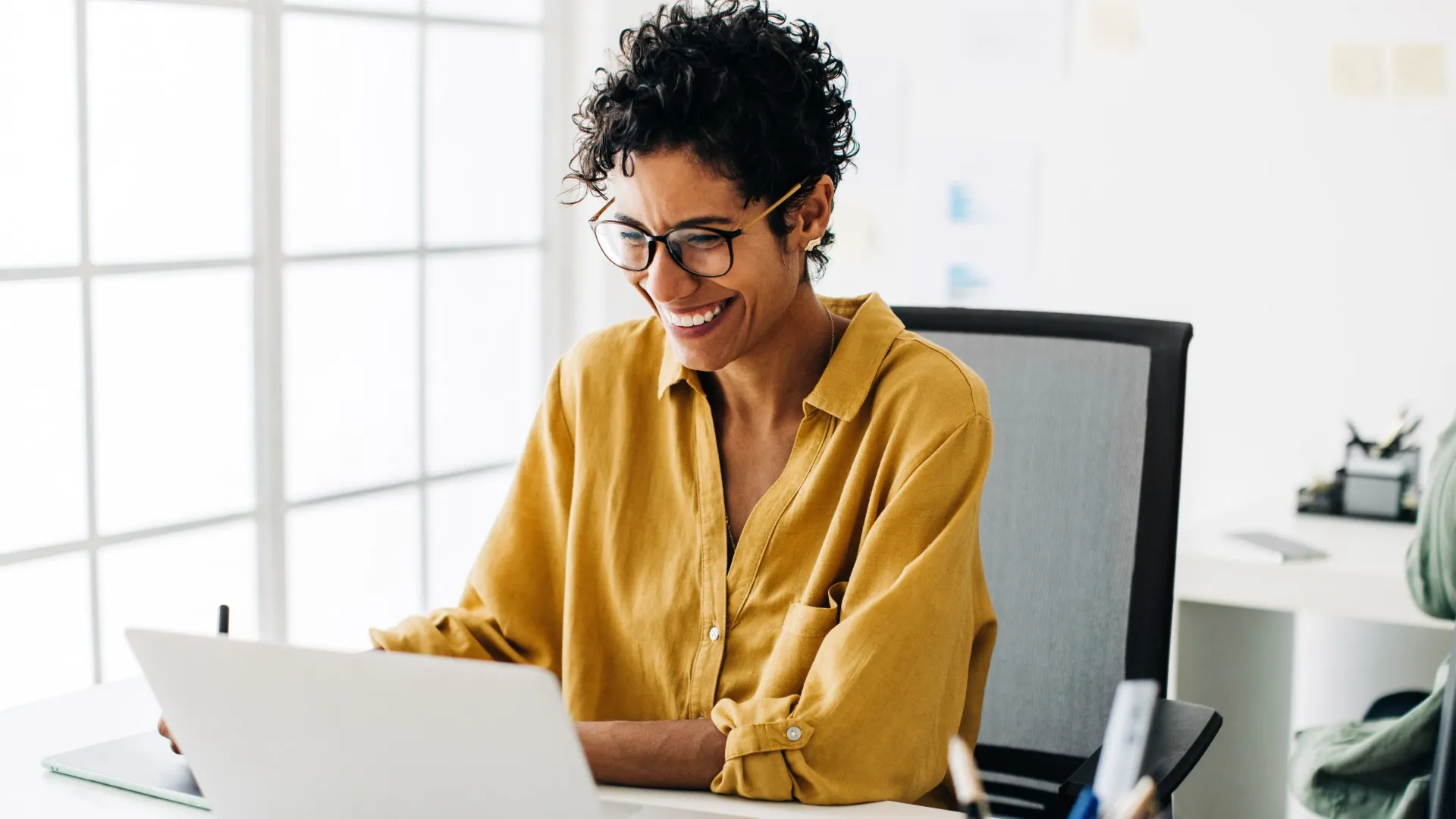 A woman smiles while working at the office.