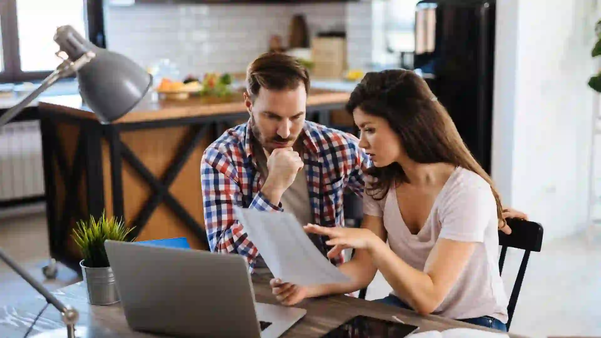 Frustrated couple checking bills at home using laptop.