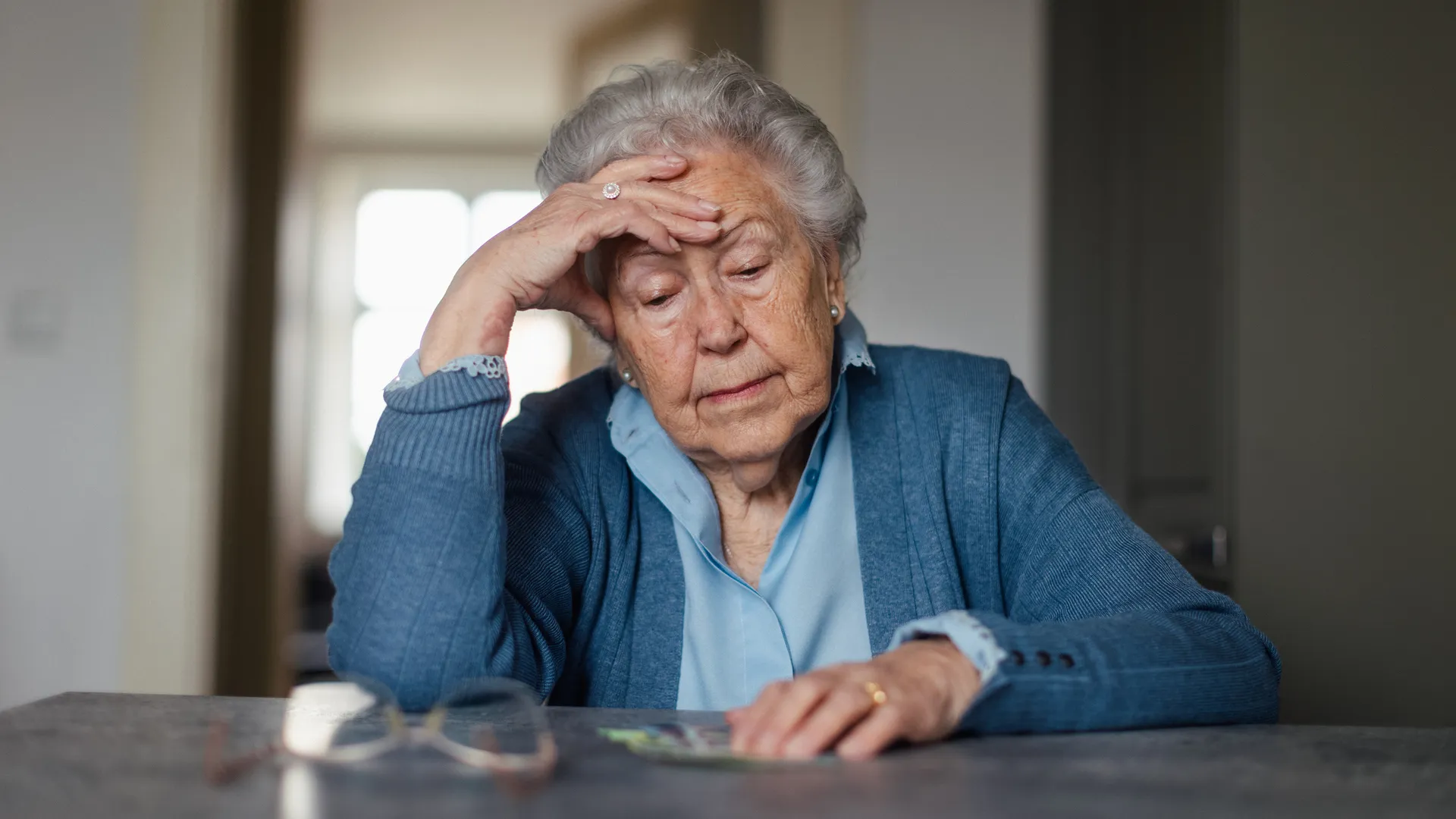 Unhappy enior woman counting her pension at home.