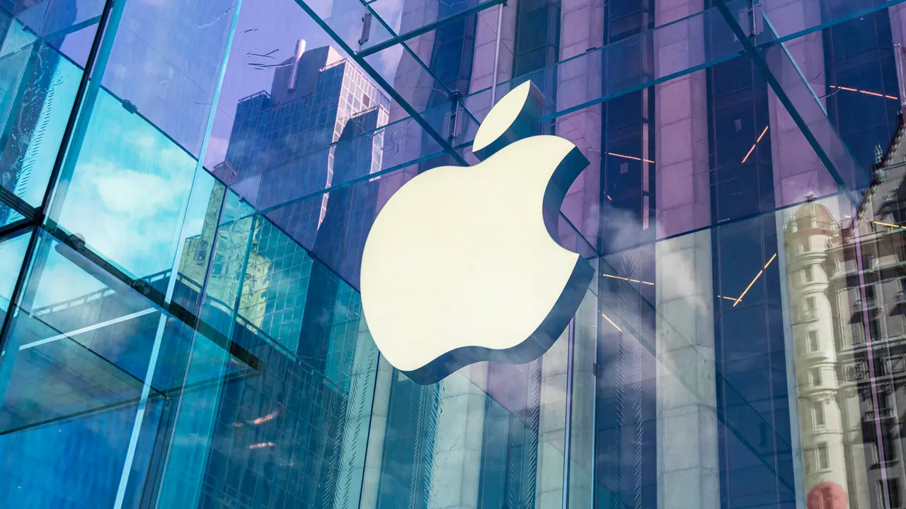 The Apple logo on the outside of a glass building in the city.