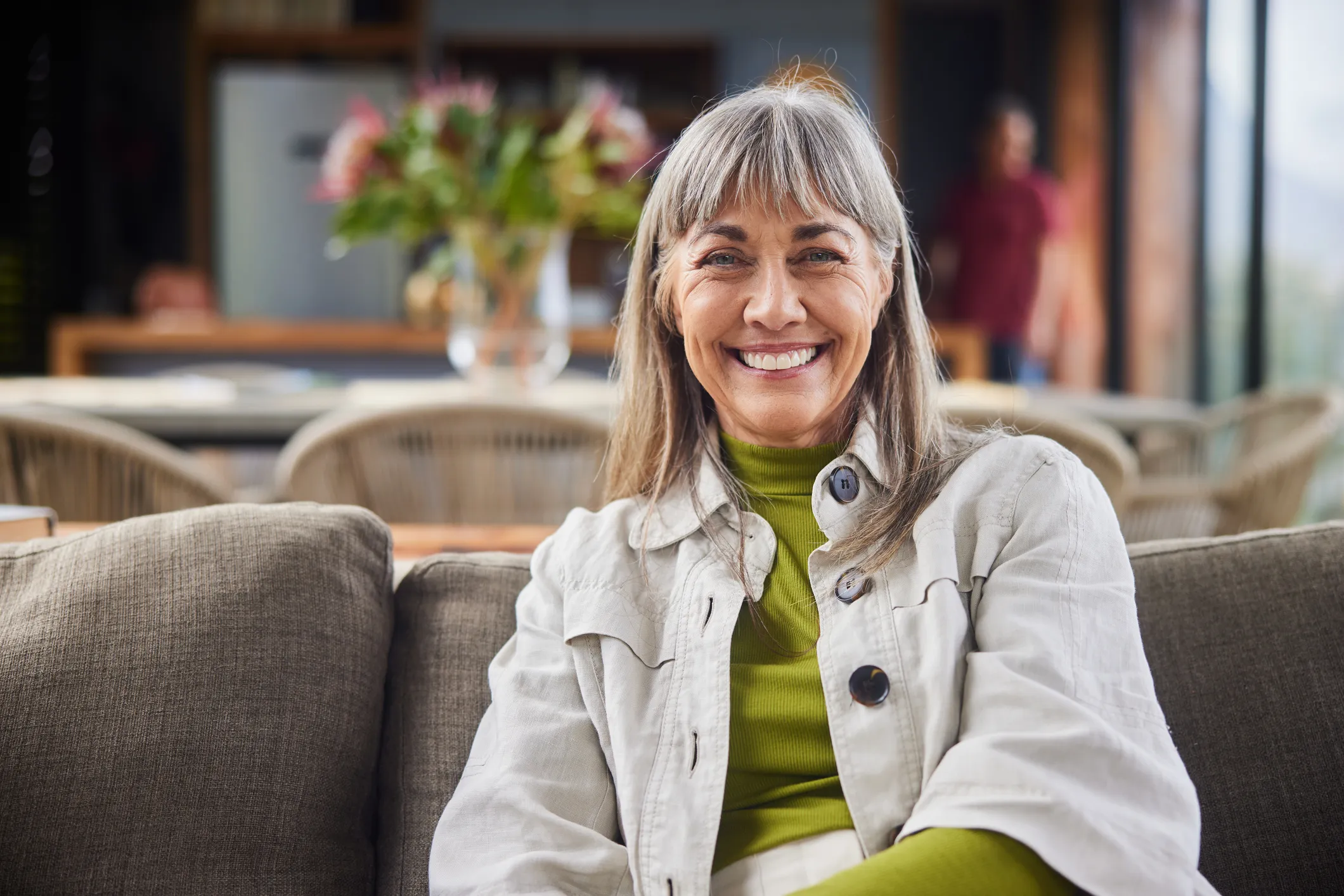 Mature woman smiling while relaxing on a sofa in the living room of her luxury home.