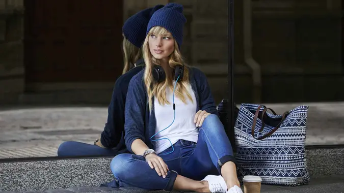 Fashion model relaxing on sidewalk in city.