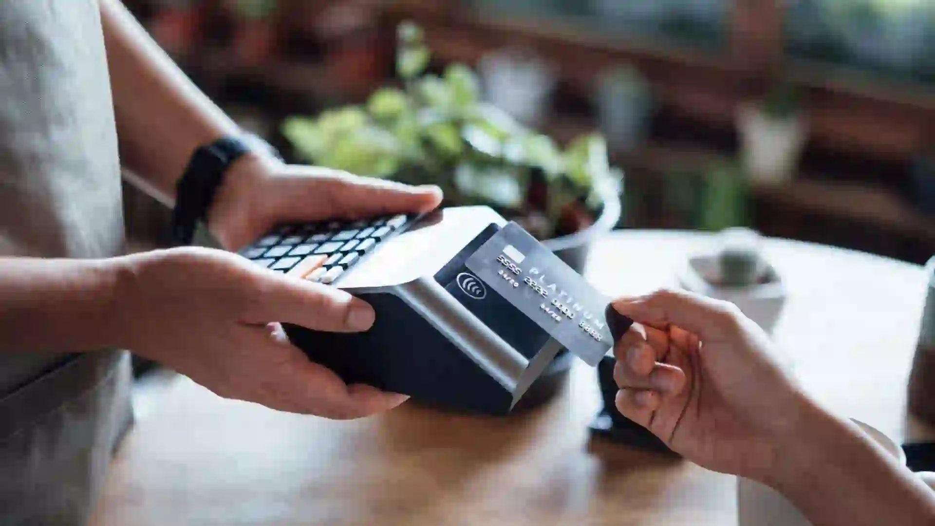 Close up of a woman's hand paying bill with credit card in a cafe, scanning on a card machine.