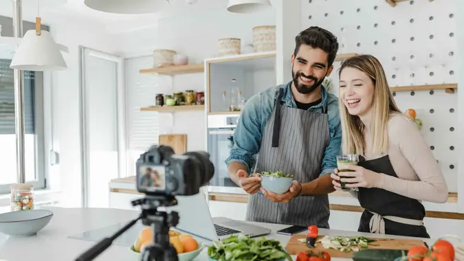A young couple of Youtubers recording a video for their channel while cooking.