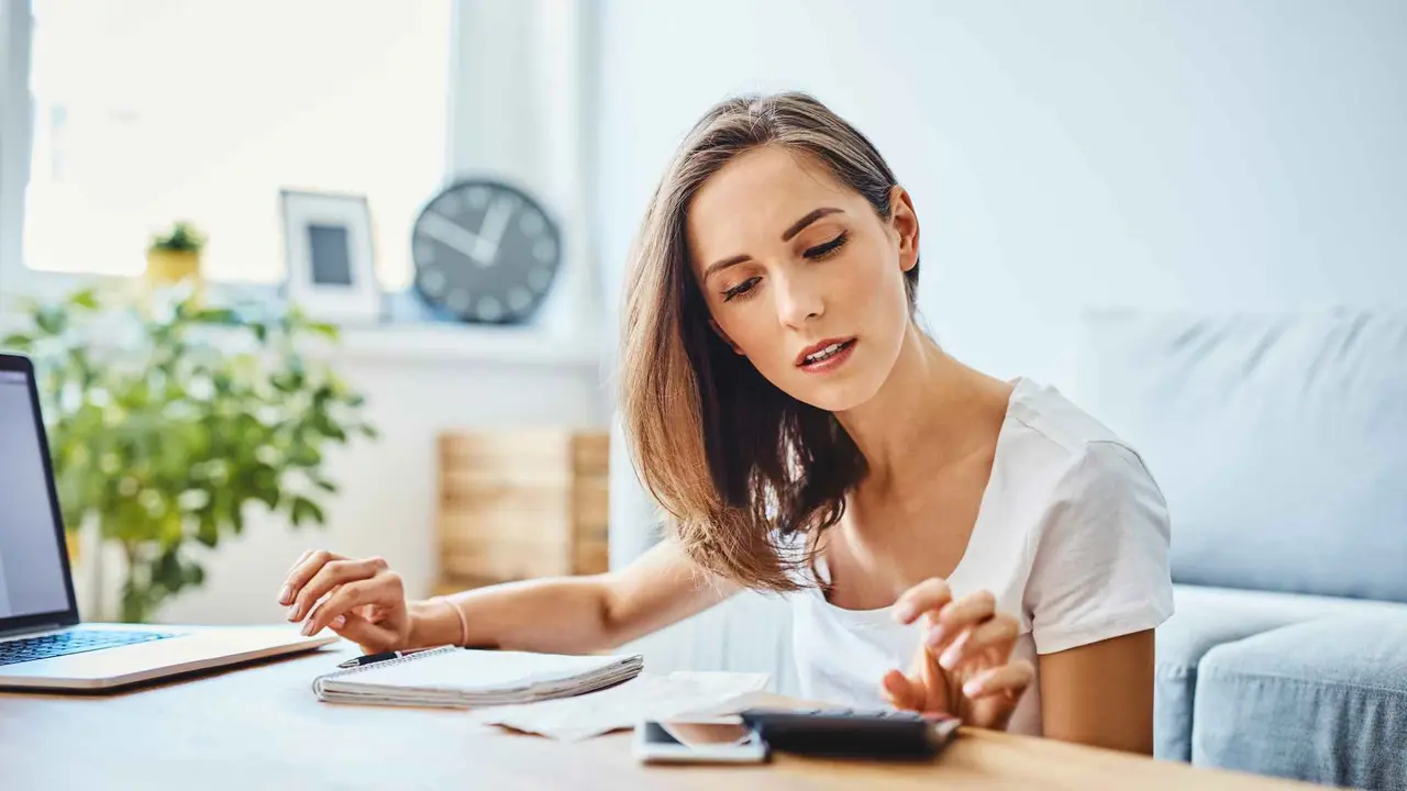 Young woman preparing home budget, using laptop and calculator.