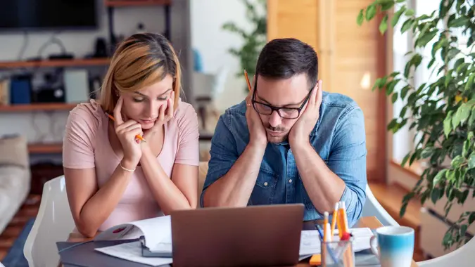 Couple checking their bills,using laptop while working at home in the living room.