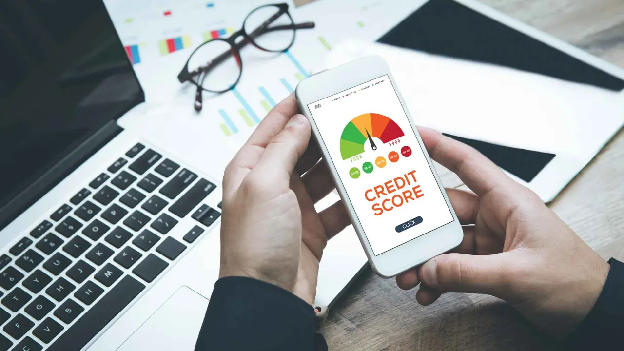A person holding a phone with their credit score on the screen.