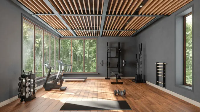 Personal Training Studio With Barbell, Dumbbells, Exercise Bike And Garden View From The Window.