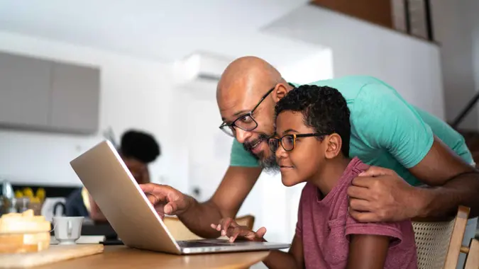 Father encouraging son on homeschooling or doing a video call/watching a movie.