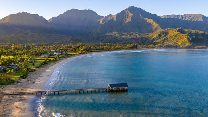 Aerial panoramic image at sunrise off the coast over Hanalei Bay and pier on Hawaiian island of Kauai.