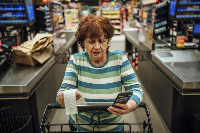 Senior woman with a smartphone checking the bill after shopping at the supermarket.