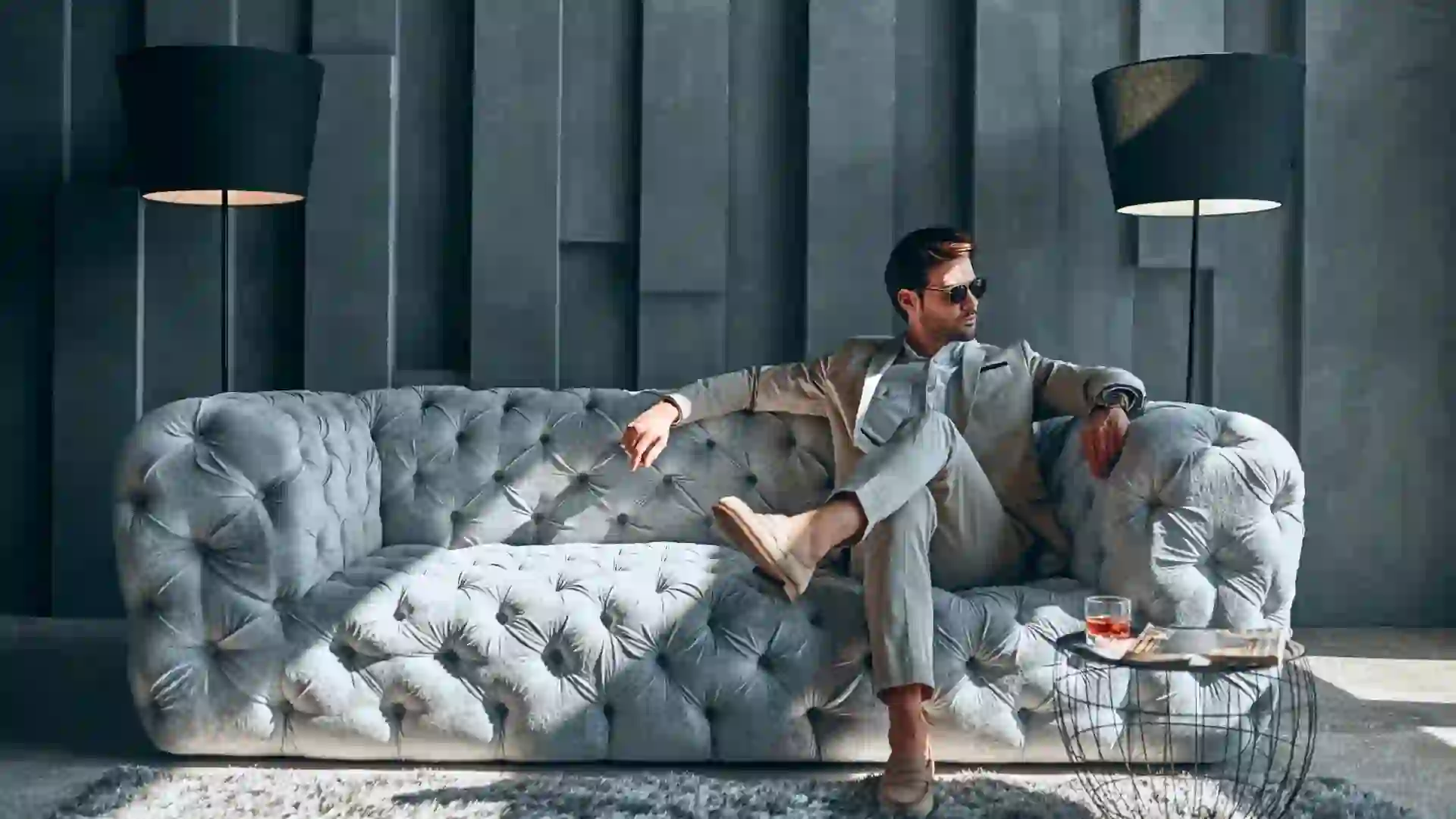 Handsome stylish man in beige suit at home sitting on sofa.