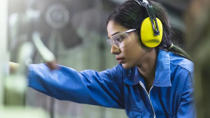 Portrait asian female Professional engineering wearing uniform and safety goggles Quality control, maintenance, monitor screen checking process in factory, warehouse Workshop for factory operators stock photo