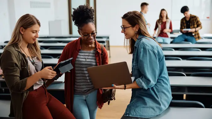 Happy female students using wireless technology in lecture hall. stock photo