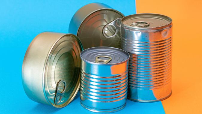 A Group of Stacked Tin Cans with Blank Edges on Split Blue and Orange Background.