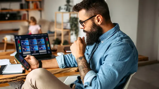 Cryptocurrency investor trading at home using his laptop stock photo