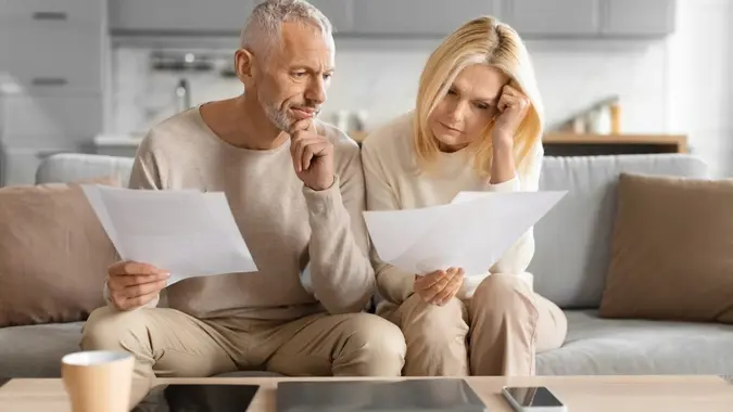 Concerned couple reviewing papers with serious faces stock photo