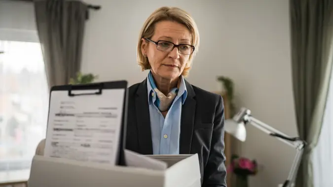 Mature woman lost her job fired from work pack personal items in box stock photo