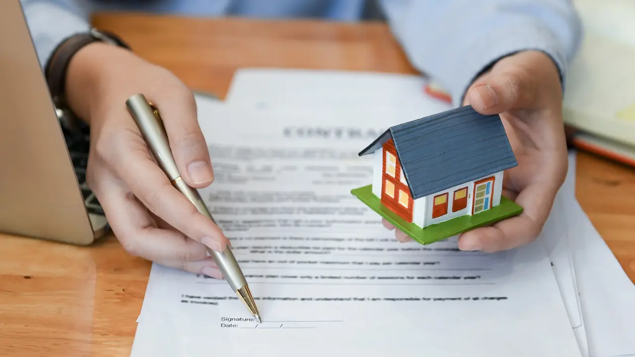 Home salesman holding a pen and model house in hand. stock photo