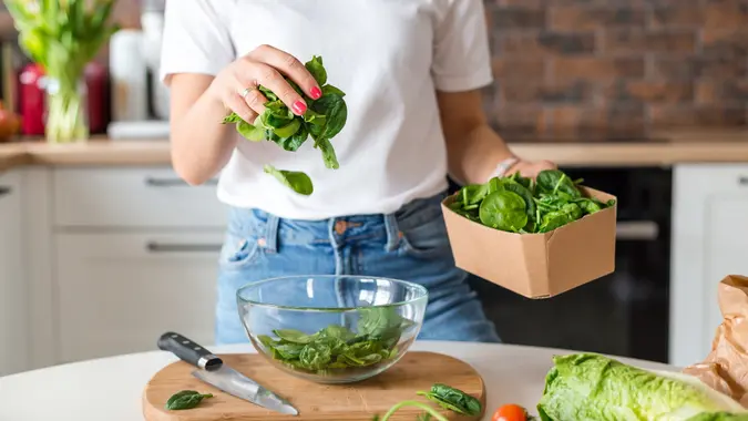 Close up woman in white t-shirt cooking salad with motion effect at home kitchen. Process of cooking healthy food, vegetable salad concept. Menu, recipe book banner stock photo