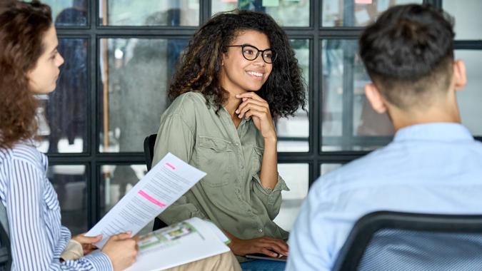 Diverse smiling happy colleagues listening to mentor leader in modern office. stock photo