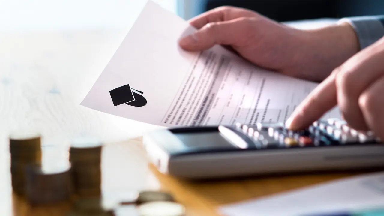 Man counting college savings fund, tuition fee or student loan with calculator. Education price and expenses concept. Money and papers on table. stock photo