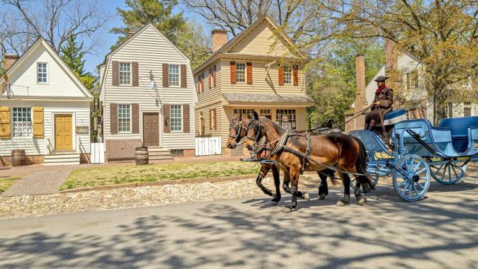 Williamsburg, Virginia, USA: April 13 2022; Actor driving a beautiful horse and carriage on a street in historic colonial Williamsburg.