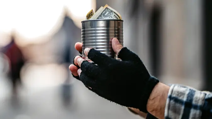 Beggar holding a can for money stock photo
