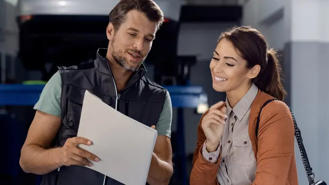 Happy mechanic and female customer going through paperwork at auto repair shop. stock photo