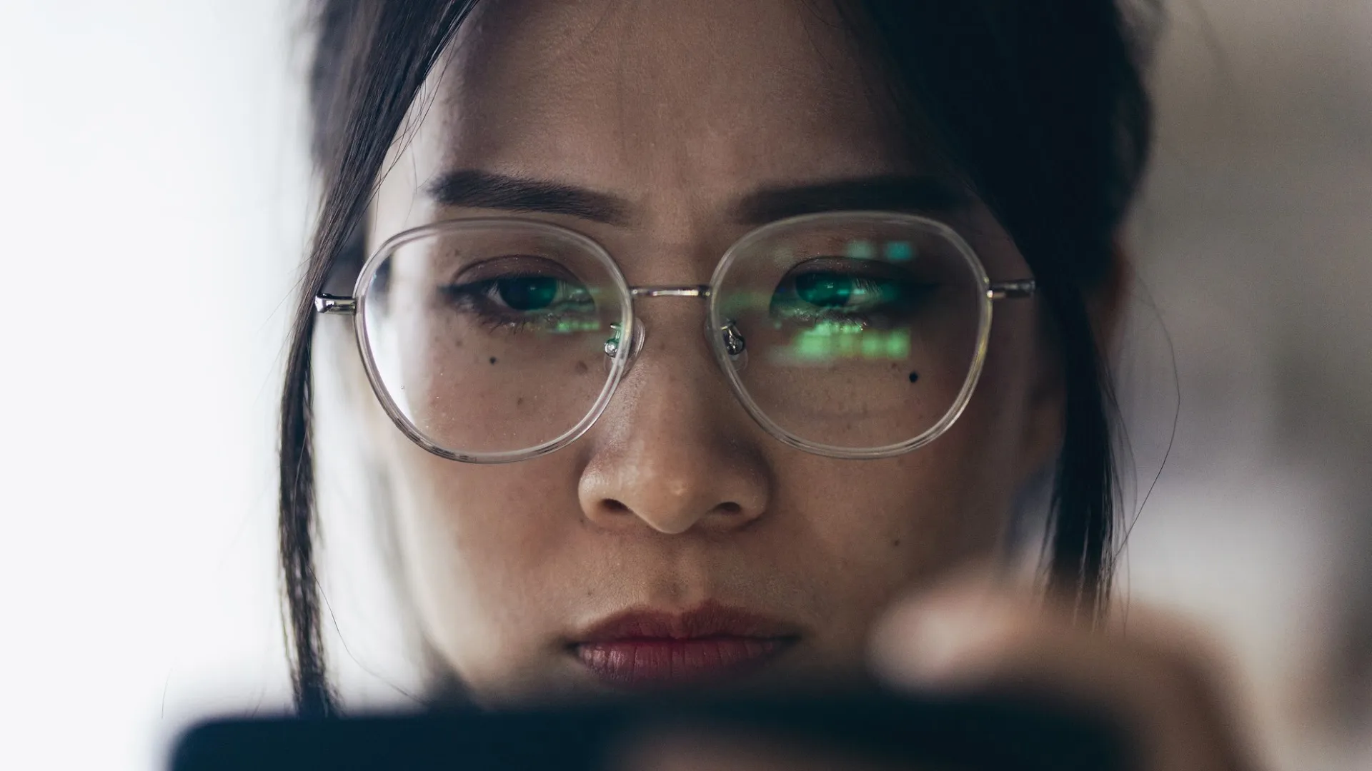 A woman is carefully observing trading charts reflected in her glasses at home stock photo