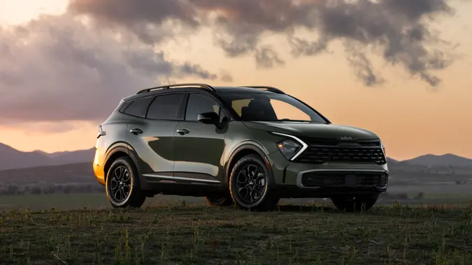 A 2025 Kia Sportage in a field with a sunset behind it