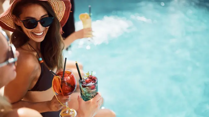 Cheerful woman having fun while toasting with her friends on summer day at the pool. stock photo