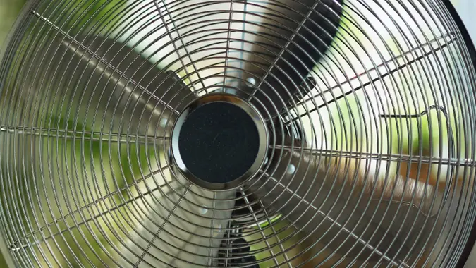 Modern metallic floor stand electric fan inside home cooling off residents in close up stock photo.