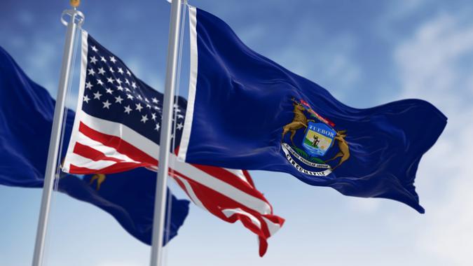 Two flags of the state of Michigan waving in the wind with the american flag stock photo