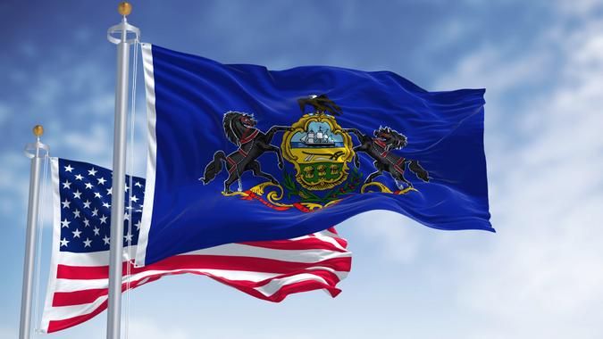 The Pennsylvania state flag waving along with the national flag of the United States of America stock photo