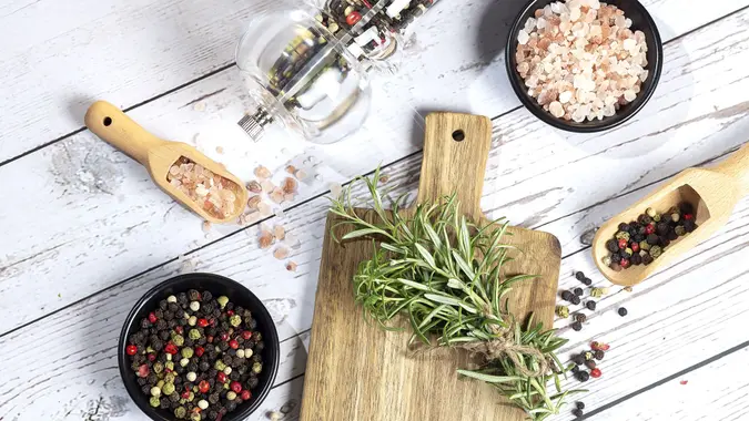 Fresh organic rosemary and pepper on woooden background.