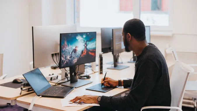 African male gaming designer, working on a new video game, drawing character sheets in the studio.