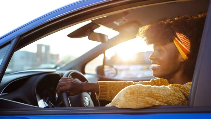 Cheerful female driver in the car while the sun sets