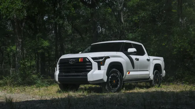 A white Toyota Tundra pickup truck parked in a field with trees behind it.