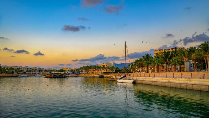 Sunset at Hawana Salalah marina with yachts, resorts and palm trees in Oman stock photo