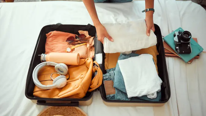 Travel packing, above and hands of a woman with clothes, holiday luggage and prepare for international summer.