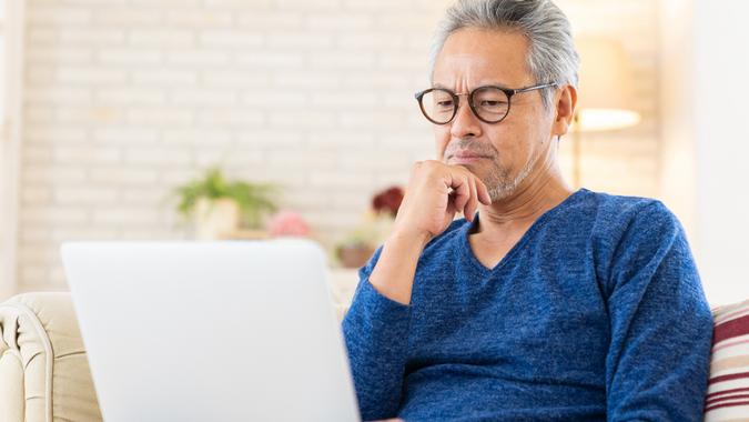 Elderly man using laptop, think, stock photo